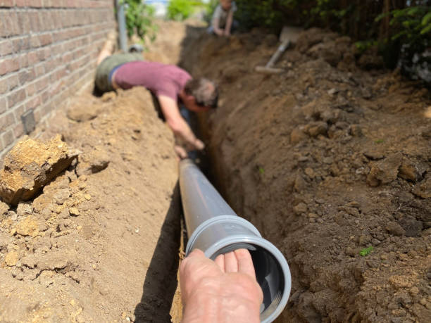 A man installing a pipe in the ground.