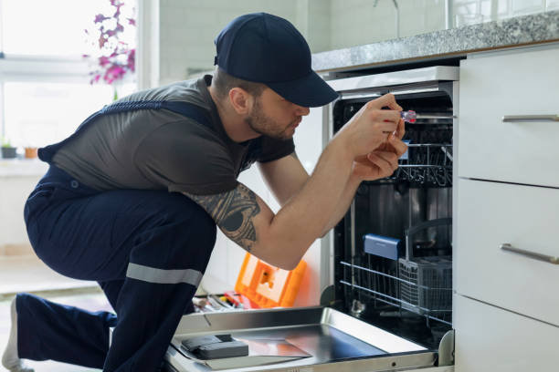 A man fixing a dishwasher in a kitchen.