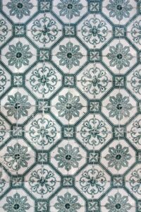 A close up of a tile with green and white designs.