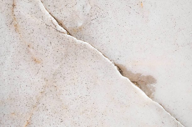 A close up of a white marble surface with cracks.