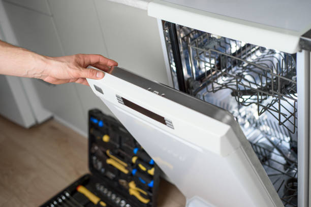 A person opening up a dishwasher with tools in it.