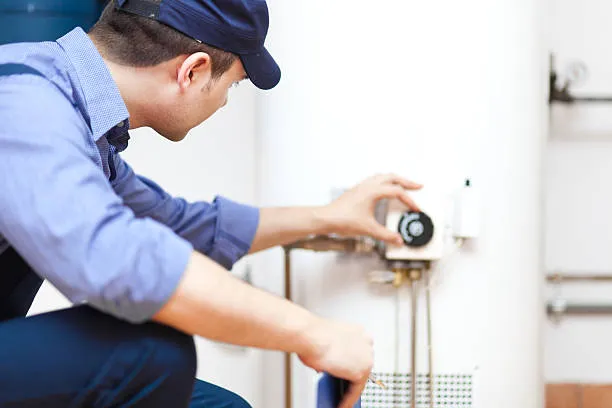 Plumber inspecting water heater thermostat for maintenance and repair.