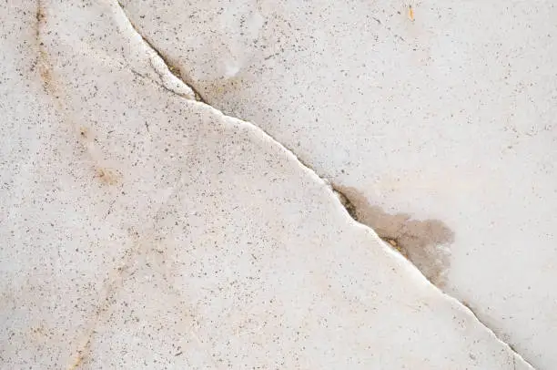 Cracked white surface with dirt and discoloration.